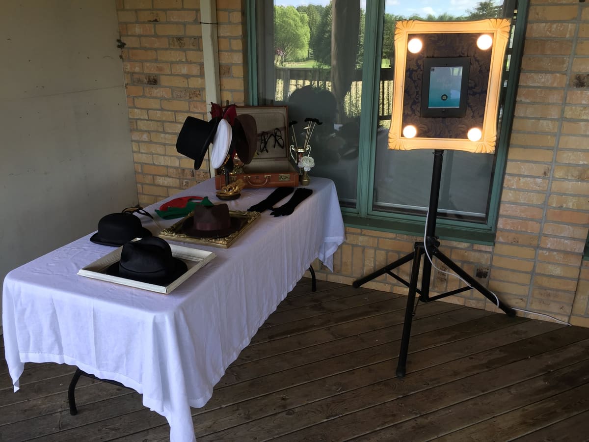 Open-air photo booth and prop table set up on a covered patio