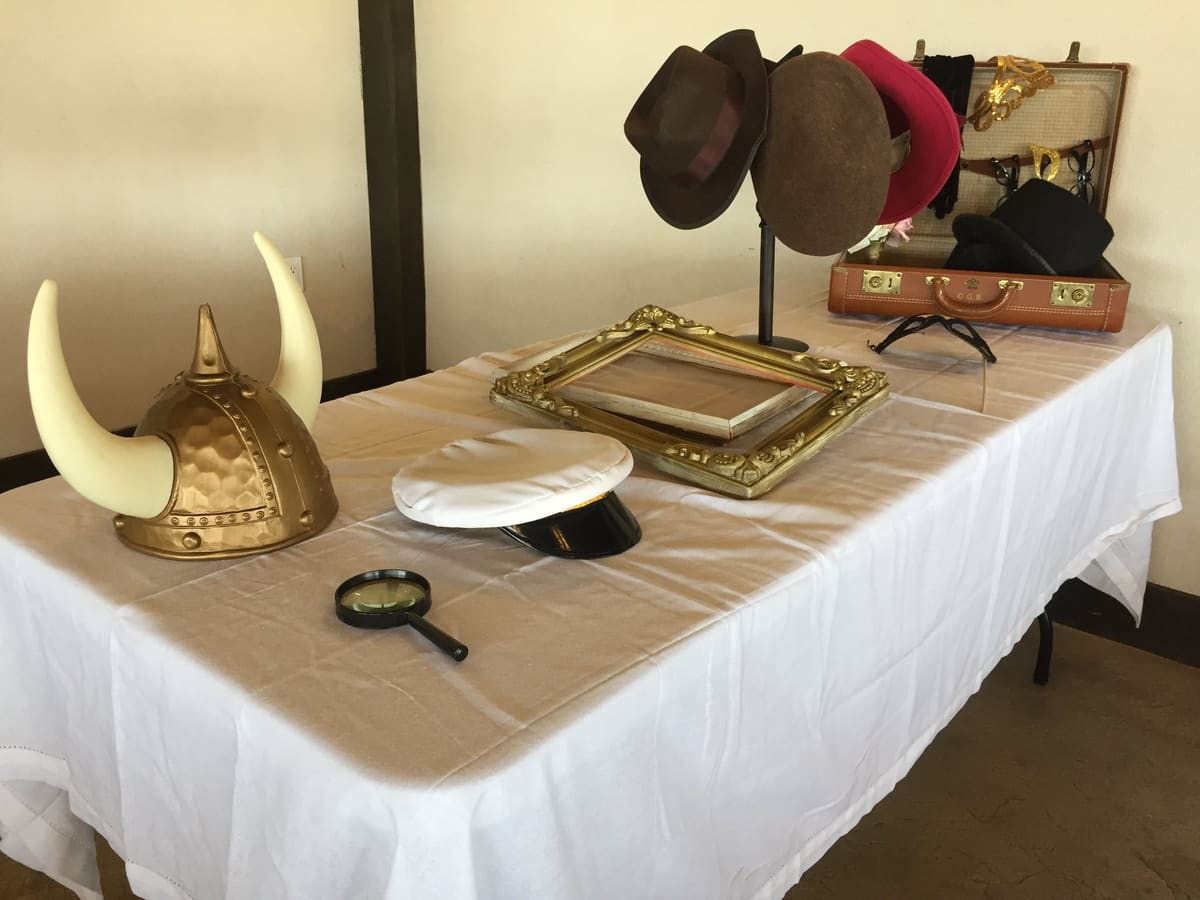 Prop table with a Viking helmet, captain hat, frames and a suitcase of props