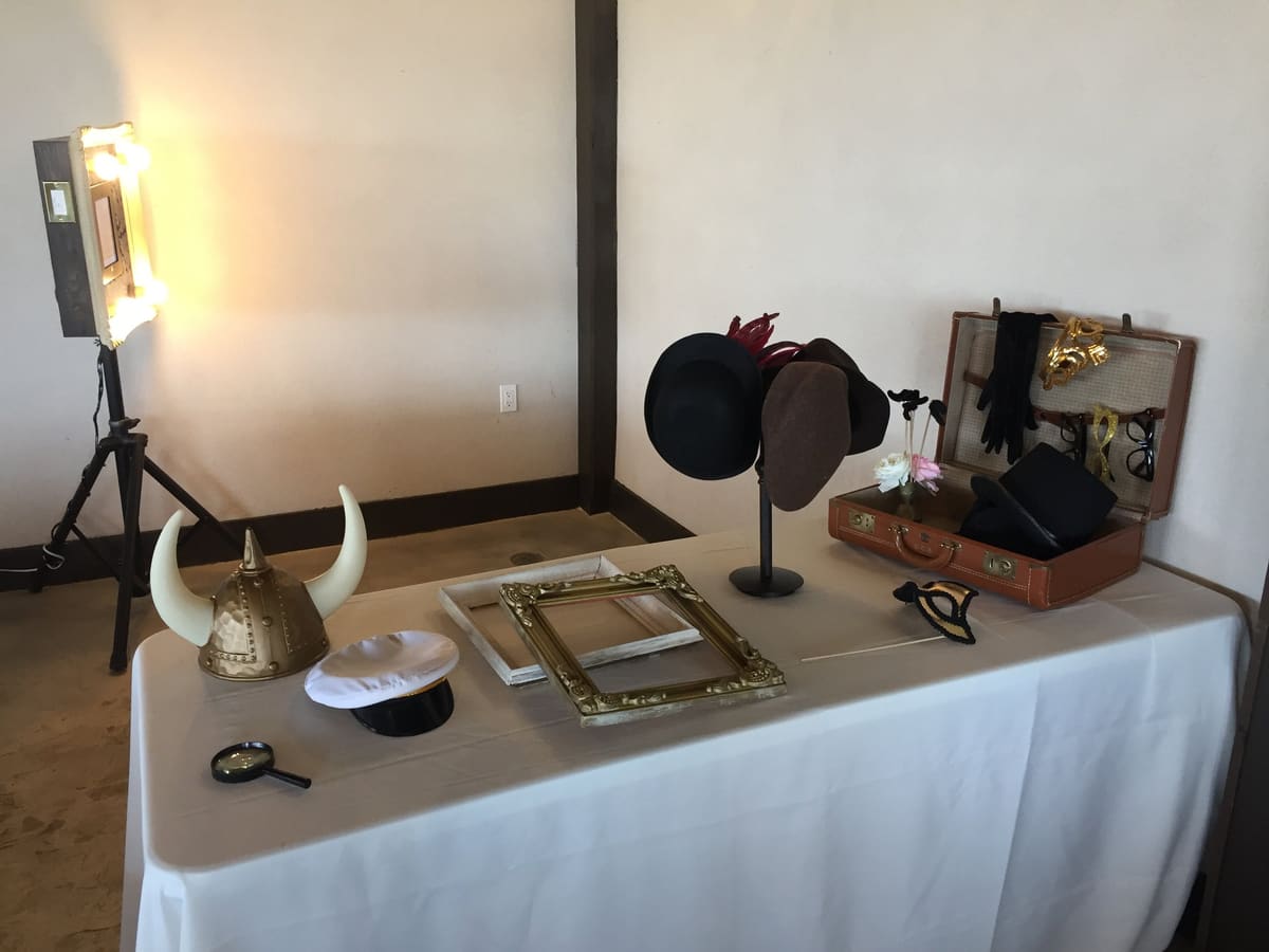 Lit photo booth beside a prop table with hats, frames and a Viking helmet